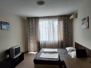 een kleine kamer met een bed en een televisie bij Апартаменти до плажа на Аурелия - между Несебър и Равда in Nesebar