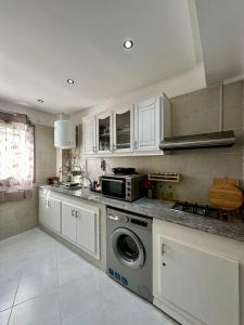 a kitchen with a washing machine and a microwave at Appart Neuf Lumineux Climatisé 1ère étage in Tangier