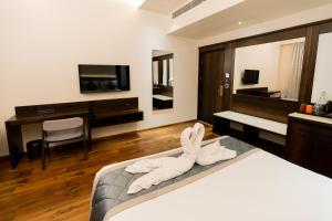 a bedroom with a bed with a towel animal on it at Hotel Le Grandeur in Narasimharaja Puram