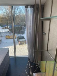 een kamer met een groot raam met uitzicht op een tuin bij Diamond Capsule Hotel Amsterdam South in Amstelveen
