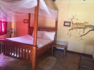 a bedroom with a canopy bed with a cheetah painting on the wall at NSYA CAMP MANYARA in Mto wa Mbu