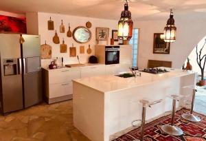 a kitchen with a refrigerator and a counter with stools at Villa Hirondelles 35 in Cavalaire-sur-Mer