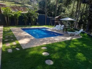 un patio trasero con una piscina con sillas y una mesa en Chacara com Piscina Aquecida, en Guarulhos