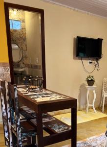 uma sala de jantar com uma mesa e uma televisão na parede em Chalé Maria Bonita - Ilha Grande, RJ em Angra dos Reis