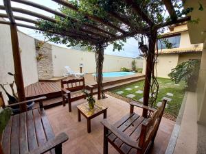 a patio with wooden benches and a swimming pool at Deu praiabuzios in Búzios