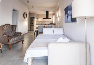 uma sala de estar com duas camas e uma cadeira em Valeria's Sea View Apartment em Atenas