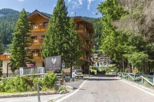 a street in a village with trees and a building at Relais San Giusto in Campitello di Fassa