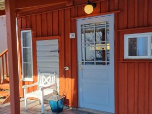 ein rotes Haus mit einer blauen Tür und einem Stuhl in der Unterkunft Hotell Park in Västervik