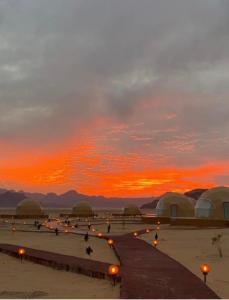 a sunset over a field with domes and lights at Wadi rum anwar luxury camp in Wadi Rum