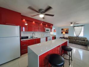 a kitchen with red cabinets and a white refrigerator at Chic 3 Bedroom Unit, Few Steps To The Ocean, Barbosa Unit 4 in Catano