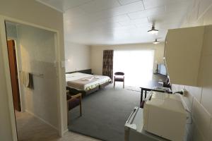 a hotel room with a bed and a desk and a window at Maple Lodge Motel in Matamata