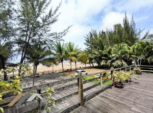 a wooden boardwalk leading to a beach with palm trees at Tim Seaside Resort by Evernent in Miri