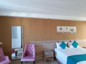 a bedroom with two beds and two pink chairs at TJ Boutique in Marsaskala