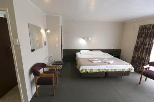 a hotel room with a bed and two chairs at Maple Lodge Motel in Matamata