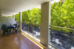 einen Balkon mit einem Tisch, Stühlen und Bäumen in der Unterkunft NEW Michelangelo Planet Costa Dorada in Salou