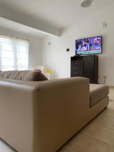 Un sofá grande en un dormitorio con TV de pantalla plana en Chalet frente al Balneario en Villa Carlos Paz