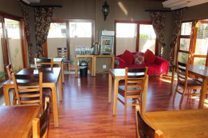 una sala de estar con mesas de madera y un sofá rojo. en Echo Garden Guesthouse, en Rustenburg