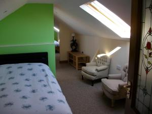 a bedroom with a bed and chairs and a green wall at Clonmacnoise B&B in Clonmacnoise