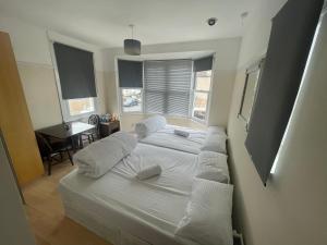 a bedroom with two beds with white sheets and pillows at Room with private bathroom and shared kitchen in London