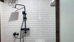 y baño con ducha y pared de ladrillo blanco. en tekMIRA Hotel, en Bandung
