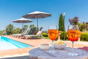 two glasses of beer on a table next to a pool at Agriturismo La Valle A Polvereto in Tavarnelle in Val di Pesa