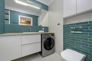 een wasmachine in een badkamer met blauwe tegels bij Unique Szczesliwa Apartment with Balcony Parking and AC by Renters in Gdańsk