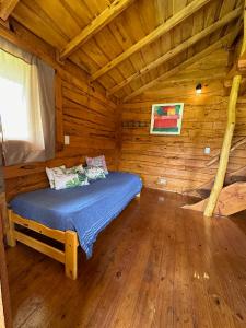 1 dormitorio con 1 cama en una cabaña de madera en Cabaña Guanumby en Tandil
