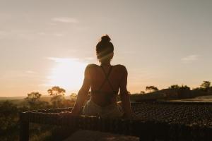 Una donna seduta su una panchina a guardare il tramonto di Casa Ônix View (15km AltoParaíso) - Viagem Inspirada a São João da Aliança