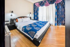 sypialnia z dużym łóżkiem z niebieską i białą pościelą w obiekcie Cron Palace kosher Tbilisi Hotel w mieście Tbilisi City