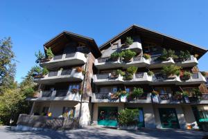 ein Apartmenthaus mit Topfpflanzen auf den Balkonen in der Unterkunft Aparthotel Edy Bruggmann AG in Flumserberg