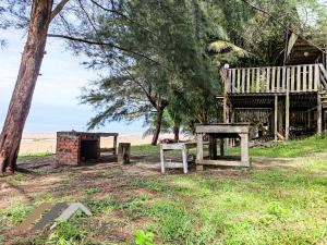 une table de pique-nique et un banc à côté d'un arbre dans l'établissement Tim Seaside Resort by Evernent, à Miri