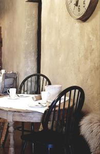 una mesa con sillas y un reloj en la pared en Le Lodge des Flâneurs, en Vielsalm