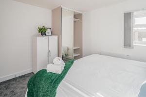a white bedroom with a bed with a towel on it at Contractors I Working professionals I Relocators - Near Train Station and Airport in Luton