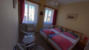 dwa łóżka w pokoju z dwoma krzesłami i oknami w obiekcie Apartman pod Zamkem w Javorníku