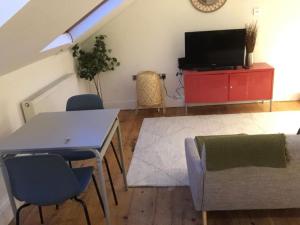 a living room with a table and a tv at Fabulous Studio Retreat - Flat 4 Highbury in London