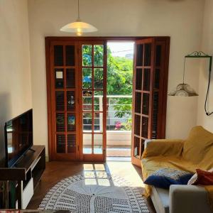 uma sala de estar com um sofá e uma porta de vidro deslizante em Apartamento na quadra da Praia de Piratininga em Niterói