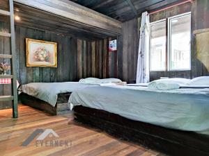 two beds in a room with wooden walls at Tim Seaside Resort by Evernent in Miri