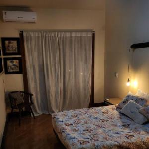 um quarto com uma cama e uma grande janela em Apartamento na quadra da Praia de Piratininga em Niterói