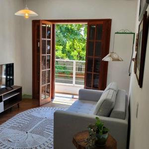 a living room with a couch and a large window at Apartamento na quadra da Praia de Piratininga in Niterói