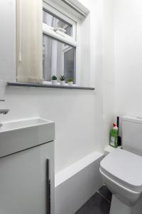 a white bathroom with a toilet and a window at Charming 5-Bedrooms in the Heart of Liverpool - By Resify in Liverpool