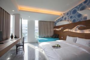 una camera con un grande letto bianco e una sedia di O-Bay Design Hotel Prachuap a Prachuap Khiri Khan
