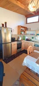 eine Küche mit einem Kühlschrank aus Edelstahl und einem Tisch in der Unterkunft Habitación Matrimonial en Totoralillo Glamping in Totoralillo