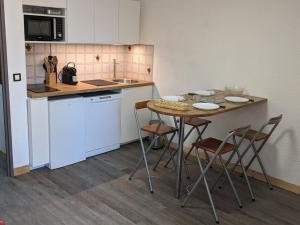 eine Küche mit Tisch und Stühlen und einer Theke in der Unterkunft Studio 4 Pers avec Loggia, Pieds des Pistes, Ascenseur et WIFI, Centre Station - FR-1-262-103 in Forest des Baniols