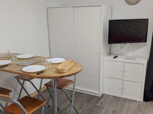 ein Zimmer mit einem Tisch mit Stühlen und einem Fernseher in der Unterkunft Studio 4 Pers avec Loggia, Pieds des Pistes, Ascenseur et WIFI, Centre Station - FR-1-262-103 in Forest des Baniols + 3 Fotos