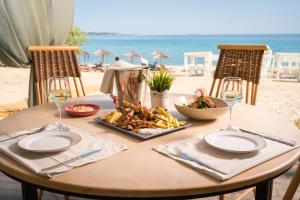 a table with a plate of food on the beach at Trypiti Resort Blue Dream Palace and Hive Water Park in Limenaria