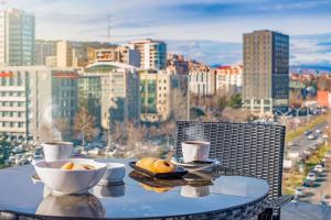 a table with two bowls of fruit on it with a city skyline at Cron Palace kosher Tbilisi Hotel in Tbilisi City