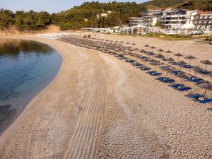a beach with umbrellas and chairs and the water at Trypiti Resort Blue Dream Palace and Hive Water Park in Limenaria