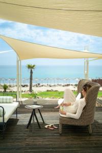two women sitting in chairs on a deck with the beach at Trypiti Resort Blue Dream Palace and Hive Water Park in Limenaria