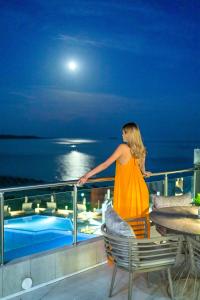 a woman standing on a balcony looking out at the ocean at Trypiti Resort Blue Dream Palace and Hive Water Park in Limenaria