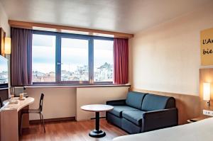 Habitación de hotel con sofá, mesa y ventana en ibis Montpellier Centre Comedie, en Montpellier